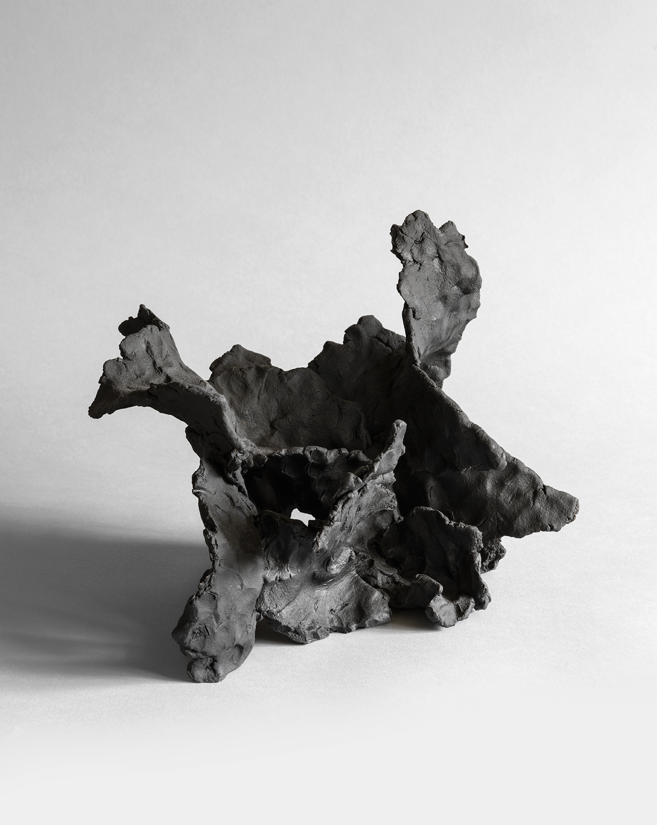 Black stoneware sculpture with flowing wave-like forms and textured organic surfaces